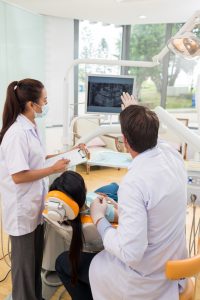 Dentist showing a patient x-ray of teeth, rear view